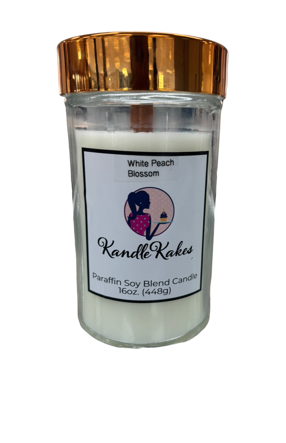 Candle in a glass jar with a gold lid on a white background, featuring a label for 'Kandle Kakes'.